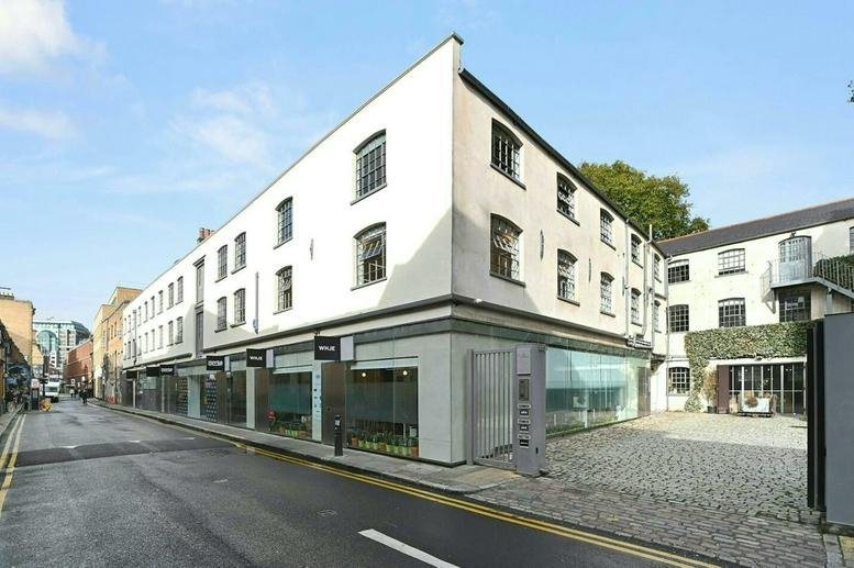 Exterior view of the white brick 11-29 Fashion Street building on a quiet city corner.