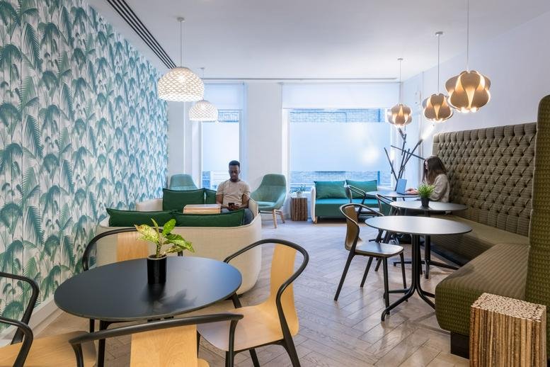 Bright communal lounge with tropical palm leaf wallpaper and modern seating.