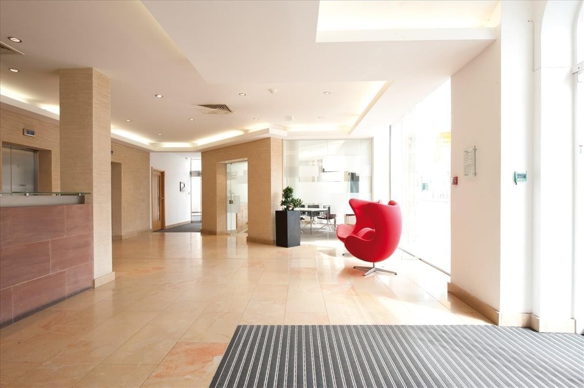 Spacious reception area at 11 Peter Street with a modern red egg chair and warm wooden flooring.