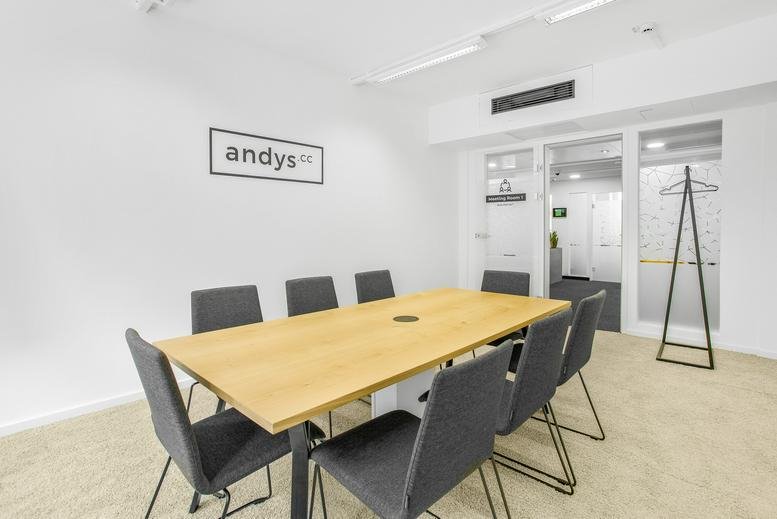 Spacious meeting room at Andys Wollzeile featuring a light wood table and modern grey chairs.