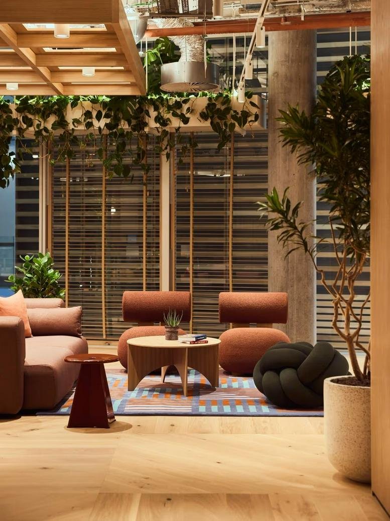 Spacious lounge at the Blue Fin Building featuring warm-toned furniture and abundant greenery.