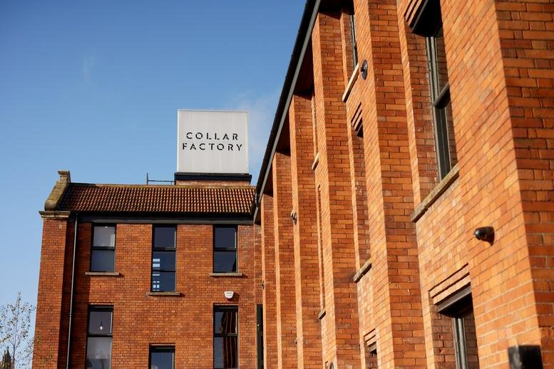 Exterior view of the red brick Collar Factory with a large rooftop sign.
