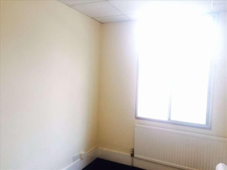 Brightly lit corner of a private office at 12 Bath Road, Hounslow, featuring a window and radiator.