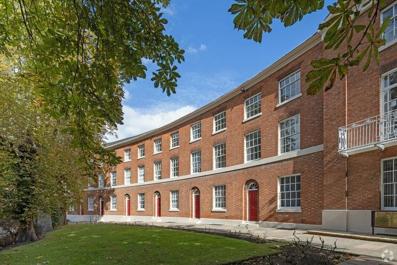 Grand brick exterior facade of 12 King Street with arched doorways and green lawn.