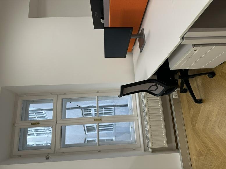 Individual workstation by a large window with natural light and a view of the street.