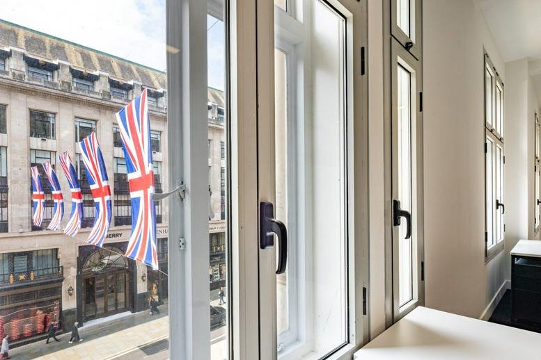 Exterior facade of 120 Regent Street, London, City of Westminster featuring classic stone architecture and British flags.