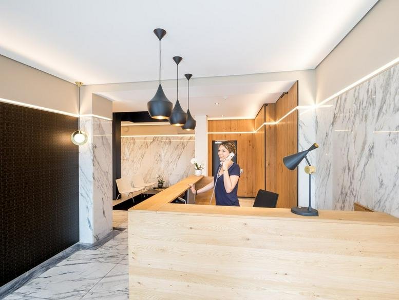 Bright reception desk made of light wood with stylish pendant lighting.