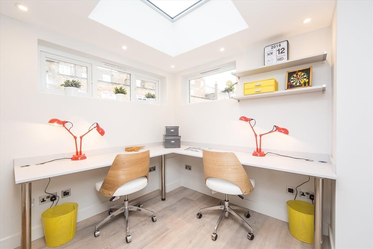 L-shaped corner workspace featuring two desks, skylight, and bright yellow accents.