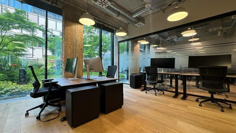 Communal lounge area at Der Junghof, featuring a wooden floor, modern furniture, and large windows.
