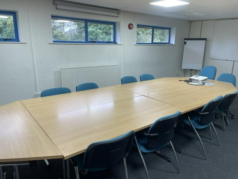 Meeting room at 14-17 Metropolitan Business Park with a large modular wooden table and blue office chairs.