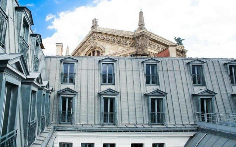 Exterior view of the historic zinc-roofed building at 15-17 Rue Scribe, Paris.