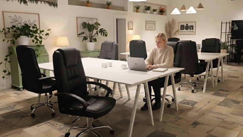 Large open-plan workspace at Bōn Coworking featuring rows of white desks and black ergonomic chairs.