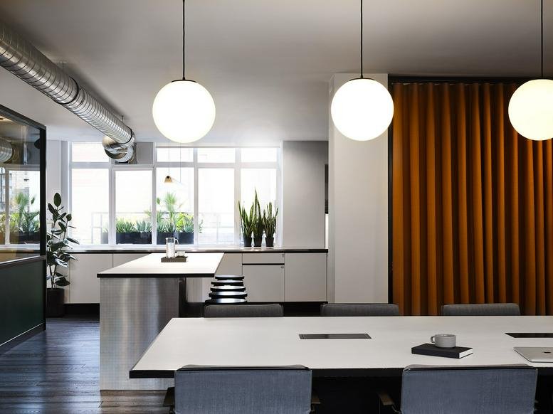 Bright open-plan kitchen area with stainless steel counters and large orb pendant lights.