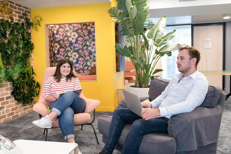 Spacious communal lounge at 16 Rue Washington featuring a yellow feature wall, floral mural, and indoor plants.