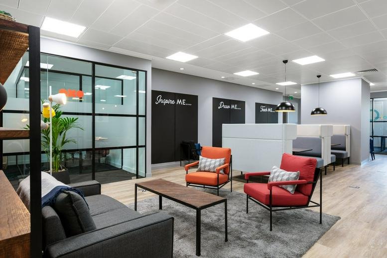 Spacious lounge at 174 Hammersmith Road with vibrant red and orange armchairs and chalkboard walls.