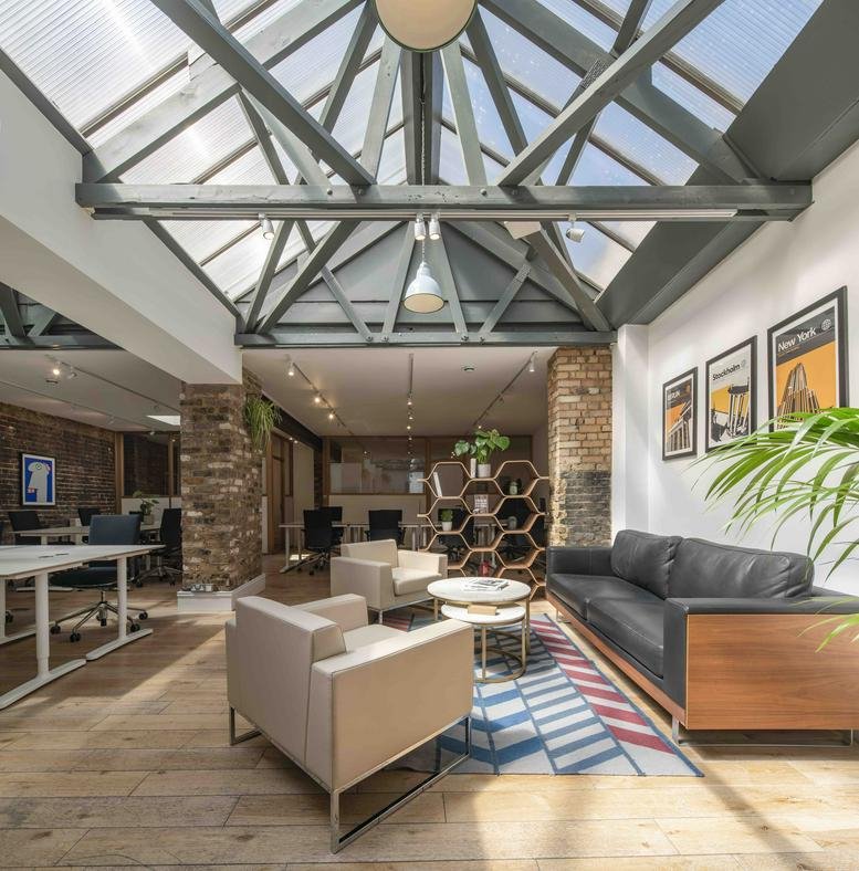 Spacious communal lounge at 189-190 Shoreditch High Street with a glass atrium roof and brick walls.