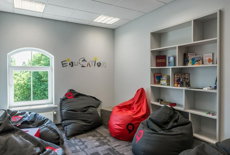 Relaxation zone with colorful beanbags and a white bookshelf.