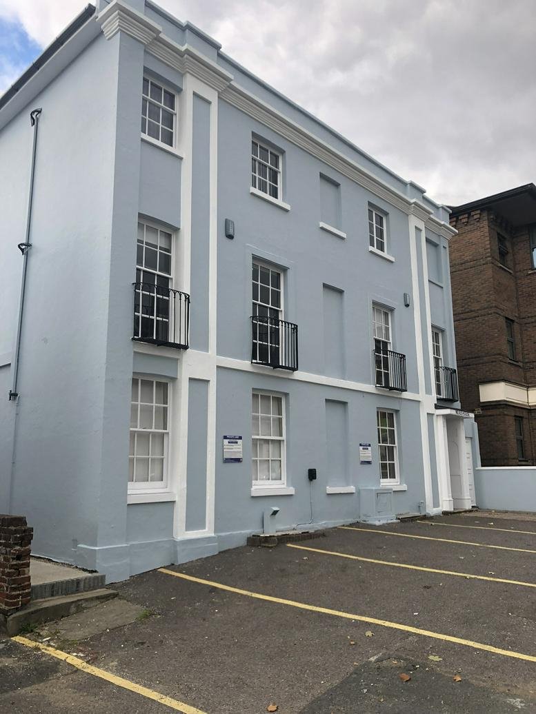 Blue three-story office building exterior with dedicated parking spaces.