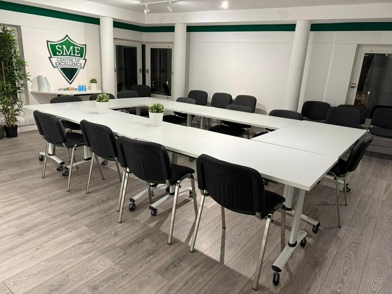 Spacious boardroom at 19 Main Street, Ponteland, featuring a U-shaped table and branded SME shield wall logo.