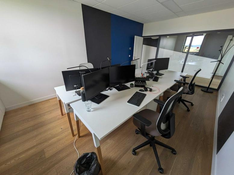 Compact two-person office with dual monitors and wooden floors.