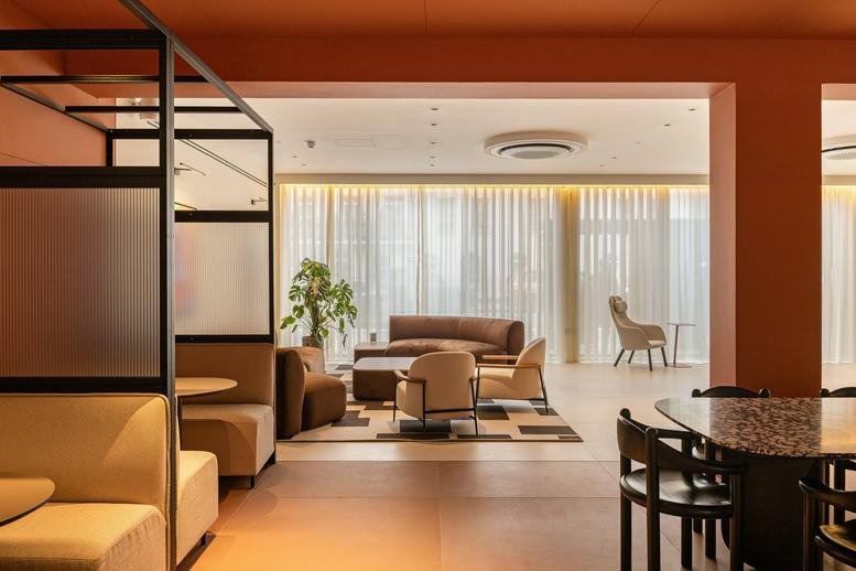 Warm, terracotta-toned lounge area at 192-198 Vauxhall Bridge Road with mid-century style furniture and plants.