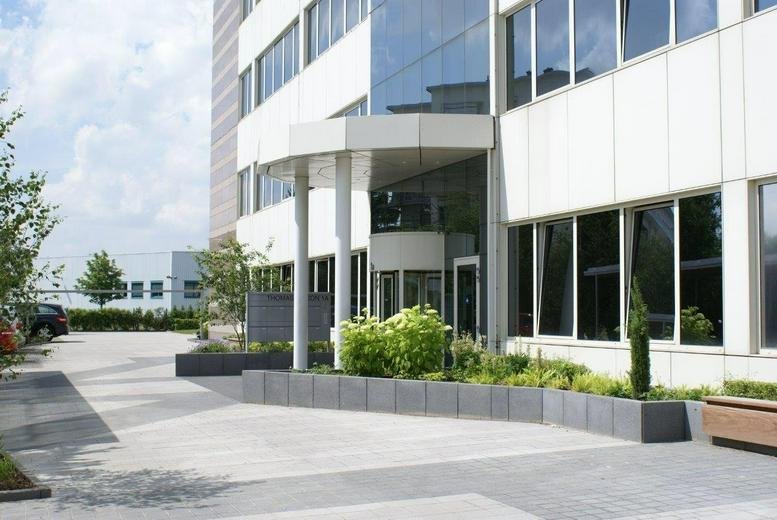 Main entrance of the Thomas Building with a modern glass facade and manicured greenery.