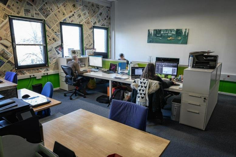 Spacious open-plan workspace at 2 Rue Pletzer, Helfent with natural light and a feature newspaper-print wall.