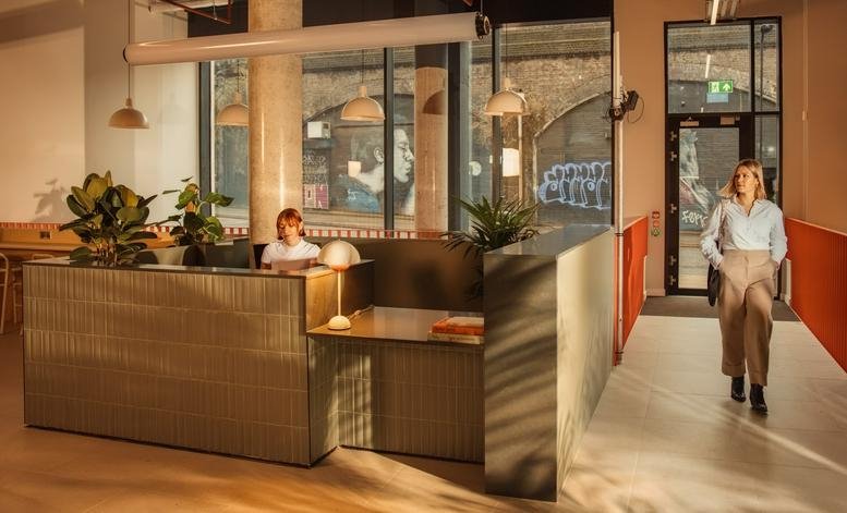 Reception area at Laundry Studios featuring a wooden desk and people moving through the space.