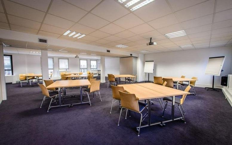 Spacious, well-lit seminar room at 20-22 Rue de Petits Hotels with multiple modular wooden tables and purple carpet.
