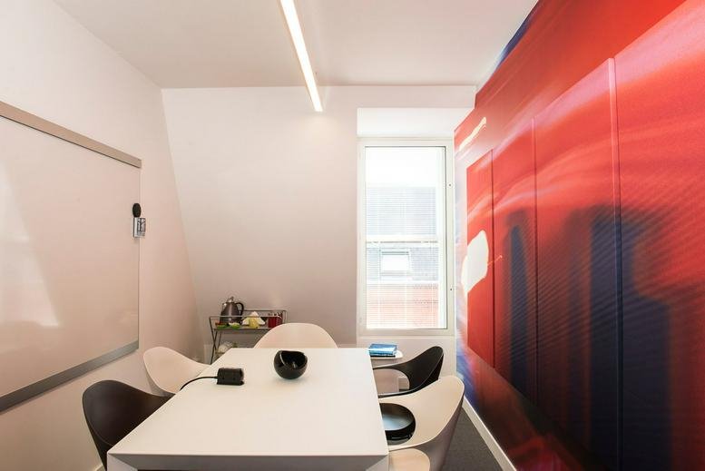 A professional meeting room at 20 Broadwick Street with a white table and a bold red abstract wall.