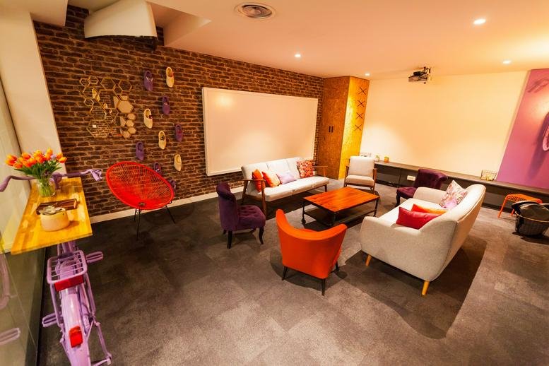Spacious communal lounge with a brick feature wall and colourful seating at 207, Rue de Bercy, Paris.