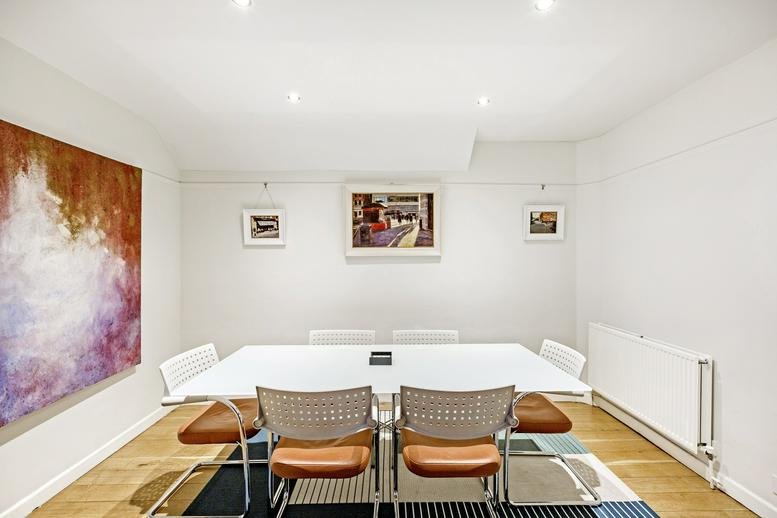 Meeting room at 21 Ellis Street with a large white table, leather chairs, and colorful abstract wall art.