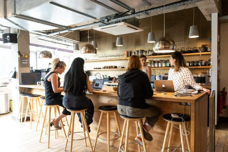 Spacious communal cafe area at The Trampery Old Street with people working at a wooden bar.