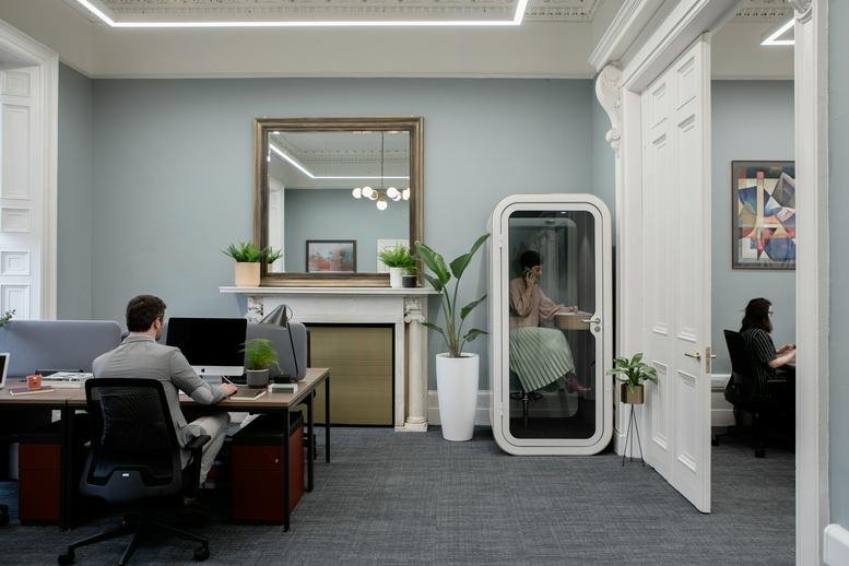 Spacious open-plan workspace at 24 Fitzwilliam Place with a classic fireplace and modern phone pod.