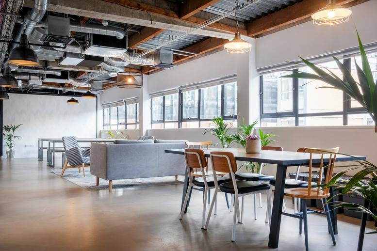 Spacious communal lounge at 25 Luke Street with industrial ceilings, large windows, and modern dining furniture.