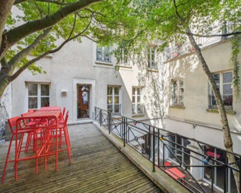 Wooden rooftop terrace with red bar tables and stools at 26 Rue Henry Monnier.