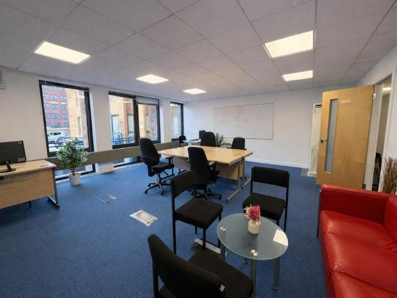 Spacious open-plan workspace at St James House, 27-43 Eastern Road with blue carpet and a red sofa.