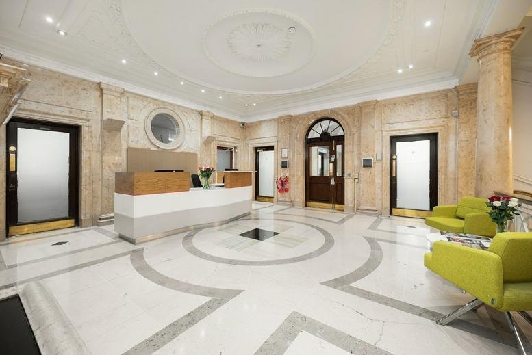 Polished marble reception lobby with a modern front desk and lime green armchairs.