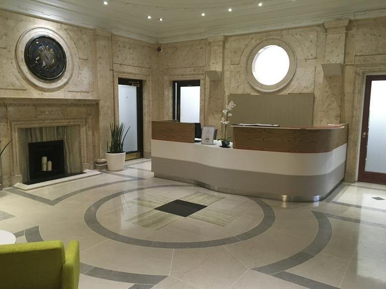 Grand lobby with a curved reception desk, marble floors, and a feature fireplace.