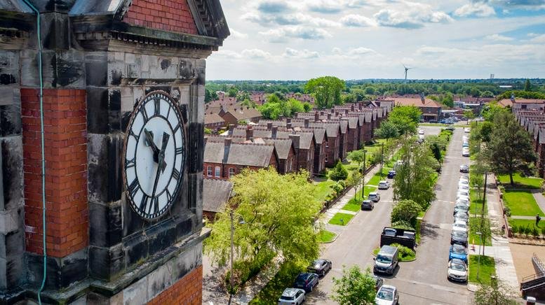 Aerial view of the brick building at 3 Clock Tower Park with a prominent clock face and surrounding neighborhood.