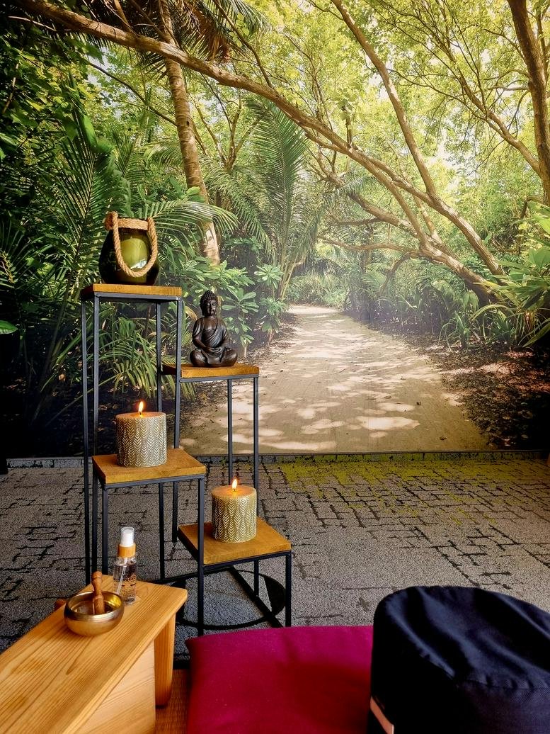 Relaxation corner featuring a forest wall mural, wooden candle stands, and meditation cushions.
