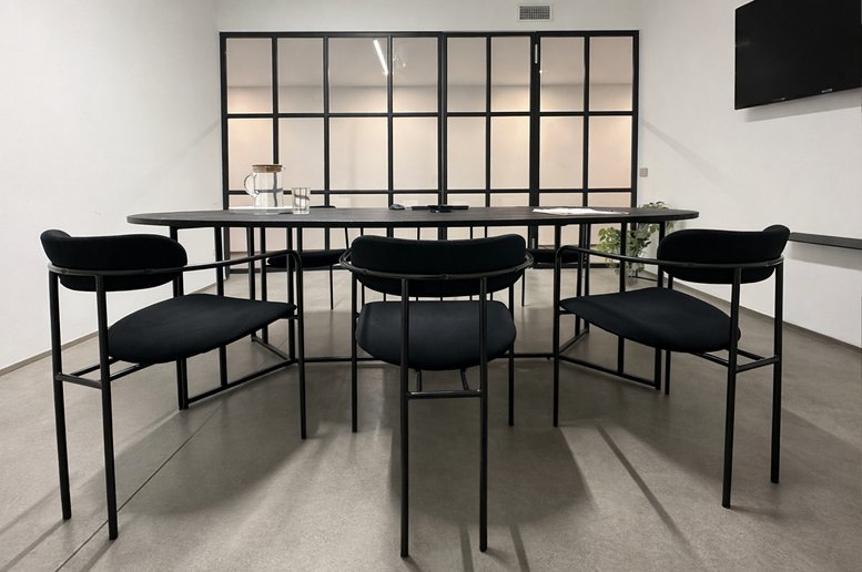 Modern meeting room with black chairs and a glass partition wall.