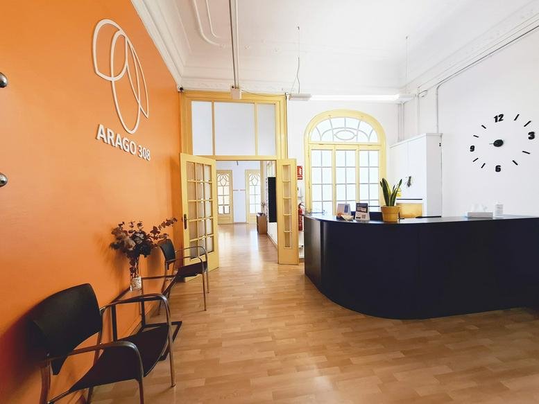 Reception area at 308 Carrer d'Aragó featuring an orange feature wall and wooden floors.