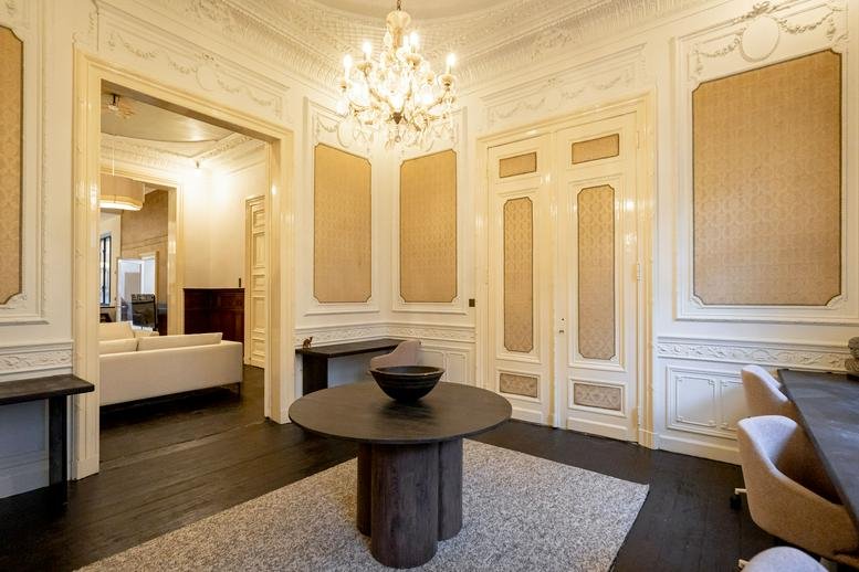 Elegant reception area of Work of Co with a crystal chandelier, dark wood floors, and decorative wall panels.