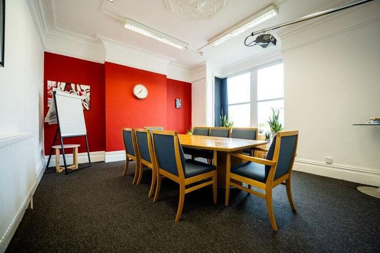 Spacious boardroom at 317 Golden Hill Lane featuring a bold red feature wall and wooden conference table.