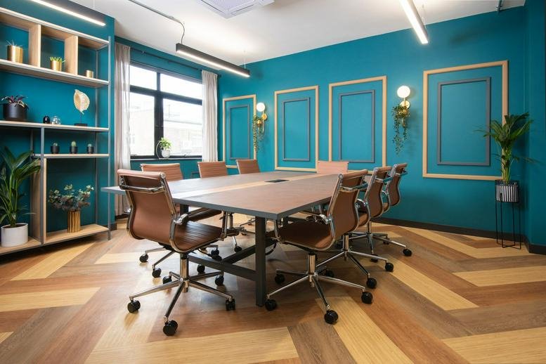 Large meeting room with teal walls and herringbone patterned wood floors.