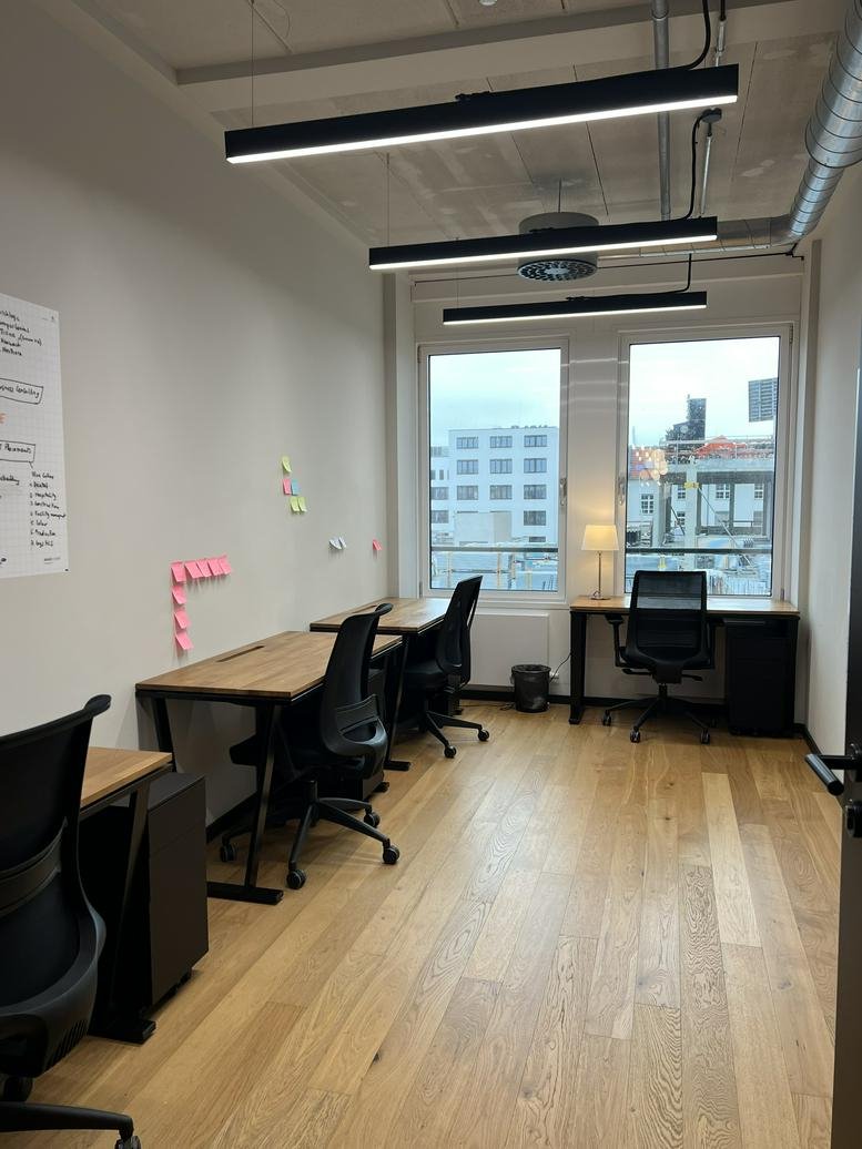 Private office at 32 Uhlandstraße with wooden desks, ergonomic chairs, and large windows with city views.