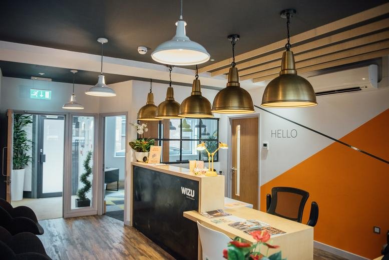 Spacious reception area with a branded desk, feature lighting, and warm wood flooring at 34 Park Cross Street.