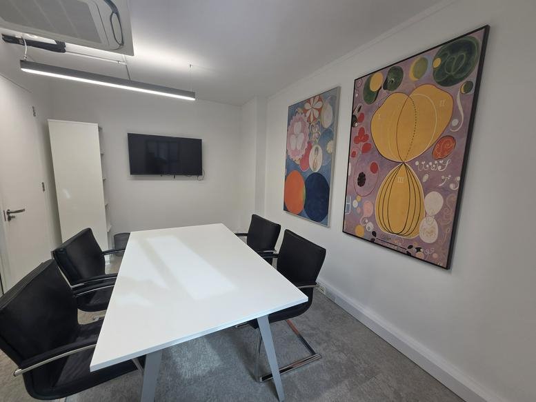 A professional meeting room at Trident House, 36 Webber Street, featuring abstract art and a white table.