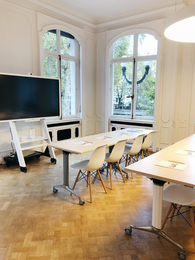 Meeting room at 367, Avenue Louise featuring a large digital screen and arched windows.